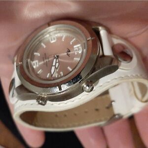 Watch with a round silver face and white leather b